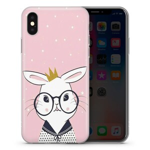 May include: A pink phone case with a white bunny wearing glasses and a gold crown. The bunny is on a pink background with white stars.