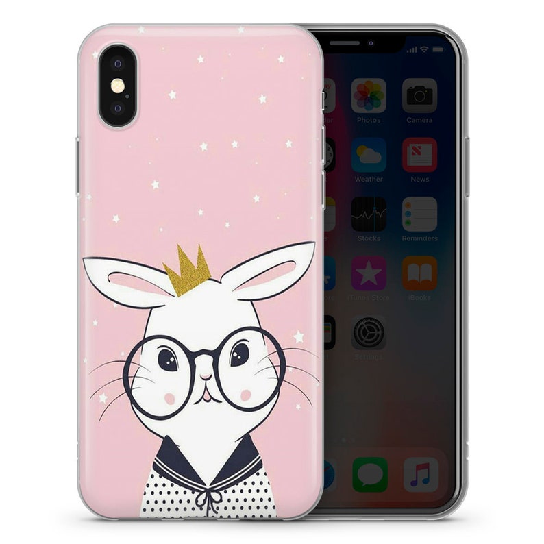 May include: A pink phone case with a white bunny wearing glasses and a gold crown. The bunny is on a pink background with white stars.