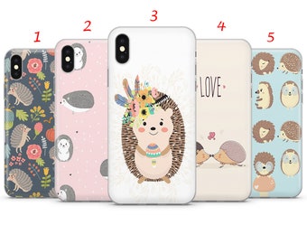 May include: Five different phone cases featuring cute hedgehog designs. The cases are white, pink, beige, and blue with various patterns and illustrations of hedgehogs. One case features a hedgehog with a flower crown, another has two hedgehogs kissing, and another has a hedgehog with a flower crown and the word "LOVE" on it.