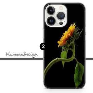 K&ouml;nnte beinhalten: Eine transparente Handyh&uuml;lle mit schwarzem Hintergrund und einer einzelnen Sonnenblume mit gelben Bl&uuml;tenbl&auml;ttern und gr&uuml;nen Bl&auml;ttern. Die Sonnenblume ist zur Seite gebogen und die Handyh&uuml;lle hat einen Ausschnitt f&uuml;r das Kameraobjektiv.