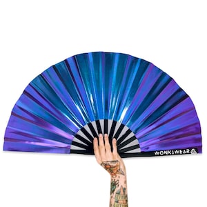 May include: A large iridescent blue and purple fan with a black and white handle. The fan is made of thin, flexible material and has a slight curve to it. The handle has the text "WONKIWEAR" printed on it.