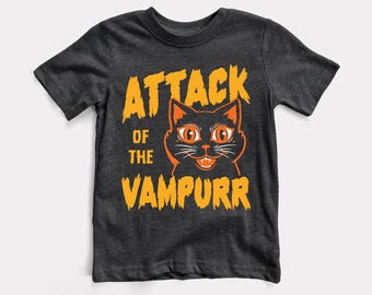 May include: A dark grey t-shirt with a black cat graphic and the text "Attack of the Vampurr" in orange.