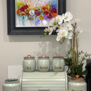 May include: Set of four green ceramic canisters with copper lids. The canisters are labelled "Tea", "Coffee", "Sugar", and "Biscuits". A green bread bin is in the centre of the image.