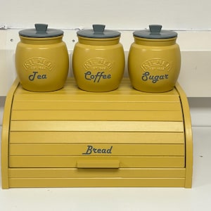 Pode incluir: Uma caixa de pão amarela com tampa de rolagem e três recipientes amarelos correspondentes etiquetados como "Chá", "Café" e "Açúcar".