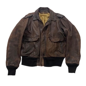 Puede incluir: Chaqueta bomber de cuero marrón con un diseño clásico. Incluye cuello, dos bolsillos delanteros y puños y dobladillo de canalé negros. La chaqueta tiene un aspecto vintage desgastado.