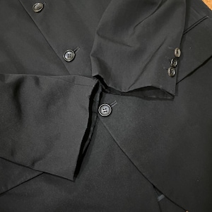 May include: Black blazer with three buttons on the sleeve and several buttons on the front. The blazer is made of a smooth fabric and has a tailored fit. The buttons are a dark color and match the blazer.