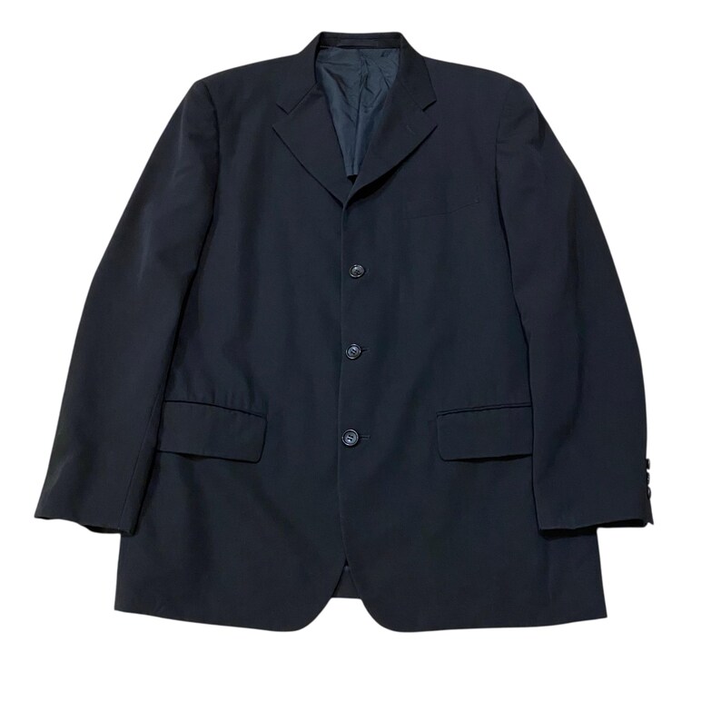 May include: A dark navy blazer with a four-button closure, two front pockets, and a notched lapel. The jacket has a classic, tailored design, suitable for formal or business attire. The blazer is a solid color and appears to be made of a smooth fabric.