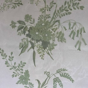 May include: A light grey surface featuring a repeating pattern of sage green botanical illustrations. The design includes clusters of daisies, delicate fern-like leaves, and slender stems with small bell-shaped flowers arranged in a floral motif.