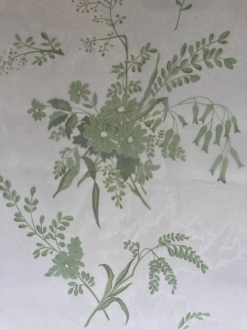 May include: A light grey surface featuring a repeating pattern of sage green botanical illustrations. The design includes clusters of daisies, delicate fern-like leaves, and slender stems with small bell-shaped flowers arranged in a floral motif.