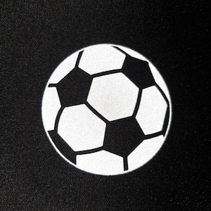 Puede incluir: Un fondo negro con un gráfico de balón de fútbol blanco y negro. El balón de fútbol está centrado y presenta un diseño clásico de pentágonos y hexágonos.