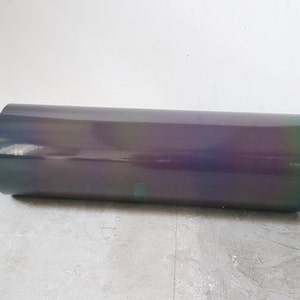 May include: A roll of iridescent holographic vinyl film with a slight green hue. The film is rolled up and has a cardboard core.
