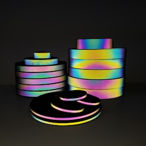 May include: A set of iridescent reflective tape rolls in various sizes. The tape is multi-coloured with a rainbow effect. The tape is stacked in a pyramid shape.