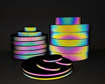 Peut inclure: Un ensemble de rouleaux de ruban réfléchissant iridescent de différentes tailles. Le ruban est multicolore avec un effet arc-en-ciel. Le ruban est empilé en forme de pyramide.