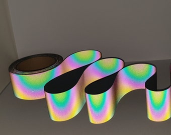 Peut inclure: Un rouleau de ruban réfléchissant arc-en-ciel iridescent. Le ruban est plié en une série de boucles, montrant l'effet arc-en-ciel.