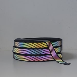 May include: A roll of iridescent black and rainbow striped ribbon. The ribbon has a diagonal stripe pattern.