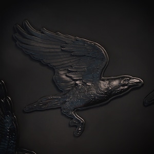 Puede incluir: Un cuervo negro en relieve en pleno vuelo, con texturas de plumas detalladas. El cuervo se representa sobre un fondo oscuro, creando un contraste dramático. La obra de arte muestra una sensación de movimiento y profundidad.