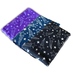 May include: Three fleece blankets in purple, navy blue, and black, each patterned with white stars and shooting stars. The blankets are soft and plush, perfect for adding a touch of celestial charm to any room.