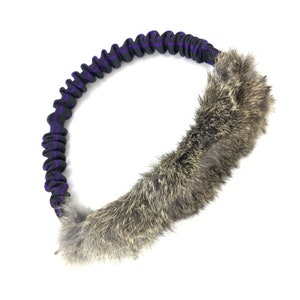 May include: A black and purple bungee cord dog toy with a brown rabbit fur tail attached.