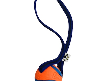 Peut inclure: Jouet pour chien en caoutchouc orange et bleu avec une sangle bleue. La sangle a une étiquette jaune avec le texte "Chuckit!"
