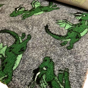 May include: Green dragon fabric with a grey background. The fabric features a repeating pattern of dragons in various poses.