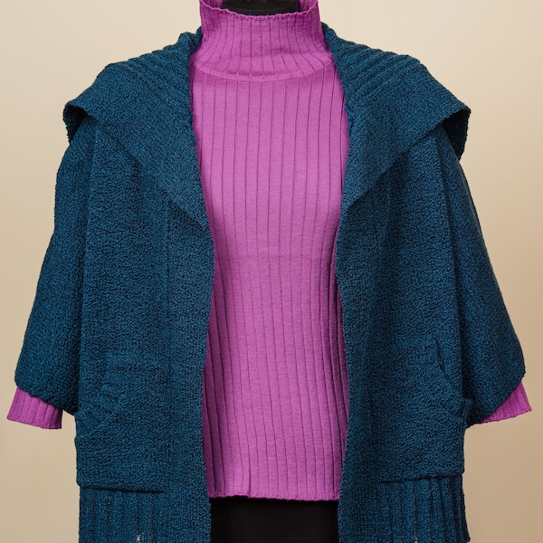 Cardigan in lana bouclè blu petrolio, con apertura e ampie tasche sul davanti,maniche 3/4 lavorato a maglia da artigiani.