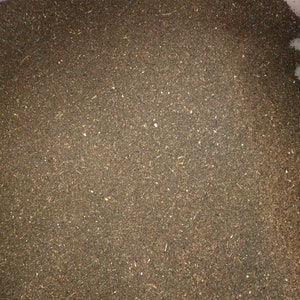 Pu&ograve; includere: Una vista ravvicinata di un grande contenitore pieno di compost marrone scuro. Il compost &egrave; composto da piccole particelle fini e sembra pronto per essere utilizzato in un giardino.