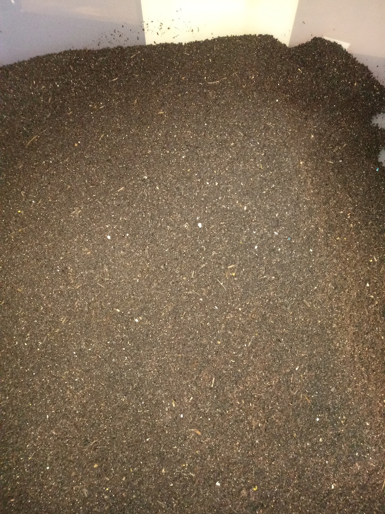 Pu&ograve; includere: Una vista ravvicinata di un grande contenitore pieno di compost marrone scuro. Il compost &egrave; composto da piccole particelle fini e sembra pronto per essere utilizzato in un giardino.