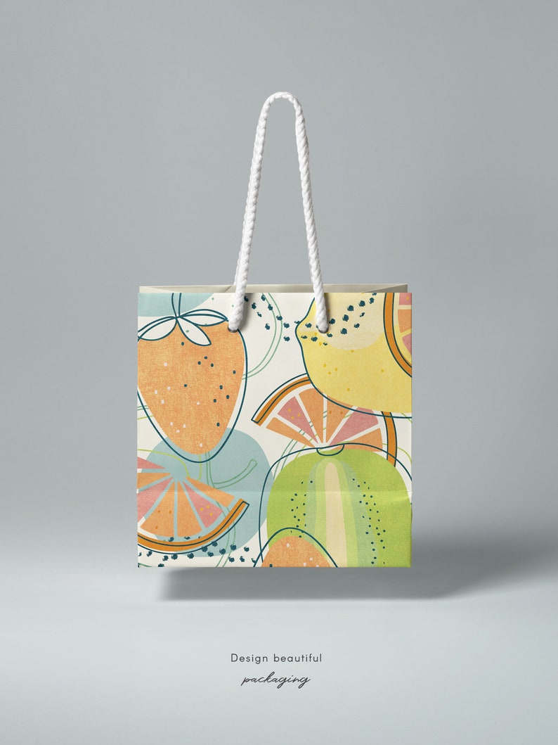 May include: A white paper shopping bag with a colorful fruit pattern. The pattern features lemons, limes, strawberries, and a green melon. The bag has white rope handles.