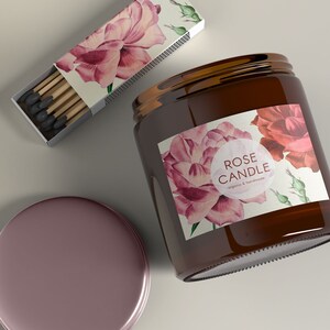 May include: A brown glass candle jar with a label that says "ROSE CANDLE organic & handmade" and features a watercolor illustration of pink roses. The candle jar is accompanied by a box of matches with a similar floral design.