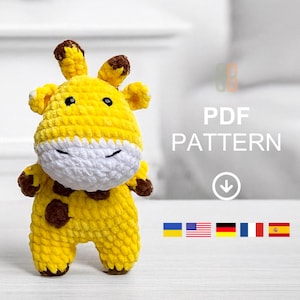 Könnte beinhalten: Eine handgefertigte gelbe Häkelgiraffe mit braunen Flecken und Akzenten. Die Giraffe hat eine weiße Schnauze und kleine schwarze Augen. Das Bild enthält den Text "PDF PATTERN" mit einem Pfeil nach unten und Flaggen verschiedener Länder.