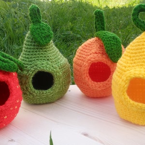 May include: Four crocheted fruit-shaped pet beds. The beds are shaped like a strawberry, pear, orange, and lemon. The beds are all made with different coloured yarn and have a hole in the front for the pet to enter.
