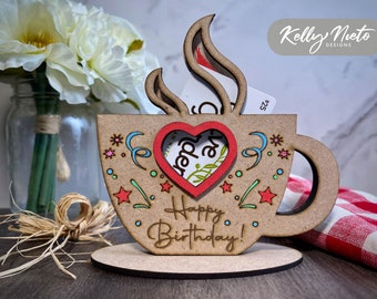 May include: A wooden coffee cup-shaped gift card holder with a red heart cutout and the words "Happy Birthday!" The cup is decorated with colorful stars and swirls. A gift card is visible inside.