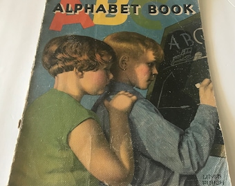 May include: Vintage ABC Alphabet Book cover featuring two children, one in a green top and the other in a blue shirt, with the title in red, yellow, and green. The boy is writing on a chalkboard. The book has a linen finish.