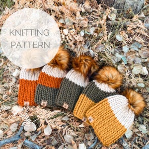 May include: Four knitted hats with faux fur pom poms in various colors, including orange, mustard yellow, green, and cream. The hats are laid out on a bed of brown leaves. The text "Knitting Pattern" is written in white on a white circle.