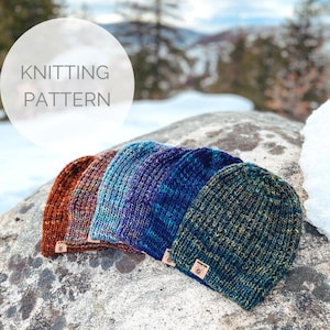 May include: Four knitted hats in different color combinations, including orange, blue, green, and black. The hats are laid out on a rock with a snowy background. The text "KNITTING PATTERN" is visible in a white circle.
