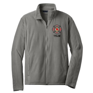 May include: A gray fleece jacket with a full-length zipper and a high collar. The jacket features a fire department emblem in red, black, and gold, with the name "TYLER" printed below the emblem. The jacket is a solid gray color.