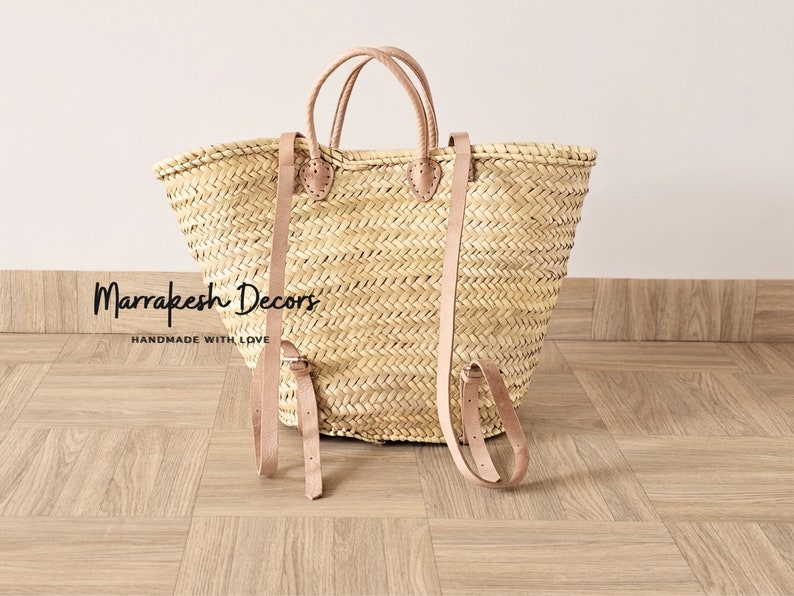 May include: A large, natural woven straw tote bag with leather straps and handles. The bag has a  "Marrakesh Decors" label and the text "Handmade with Love".