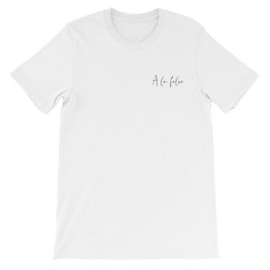 May include: White t-shirt with the text "A la folie" printed on the front in black.