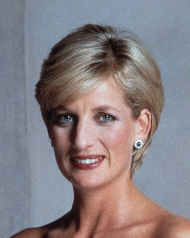 May include: A close-up portrait of a woman with short, blonde hair. She is wearing a simple, elegant outfit and has a warm, friendly smile.