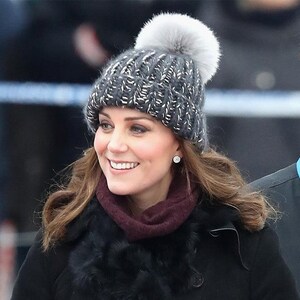 Puede incluir: Una mujer con un gorro de punto gris con un pomp&oacute;n blanco y una bufanda de piel negra. Est&aacute; sonriendo y mirando hacia la derecha.