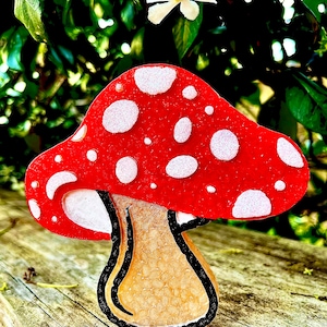 May include: A red and white mushroom figurine with white polka dots. The mushroom has a brown stem with a textured surface.