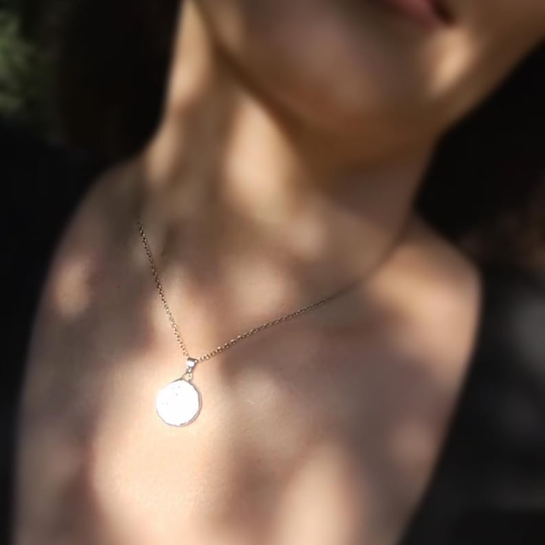May include: A silver necklace with a round pendant. The pendant is smooth and white.
