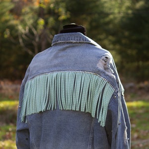 Giacca in pelle scamosciata denim usurata con frange e borchie