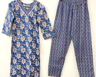 May include: A blue and white floral print cotton kurta with three-quarter sleeves and a matching pair of blue and purple chevron print pants. The kurta has a V-neckline and a white embroidered trim.