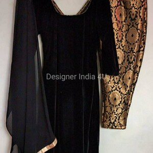 Puede incluir: Una kurta de terciopelo negro con mangas largas y cuello redondo. La kurta se combina con pantalones negros con un estampado floral dorado y negro. Se incluye una dupatta negra transparente con ribete dorado.