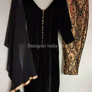 Puede incluir: Una kurta de terciopelo negro con escote en V y detalles de botones de perla. La kurta se combina con pantalones de brocado negro y dorado y una dupatta negra transparente.