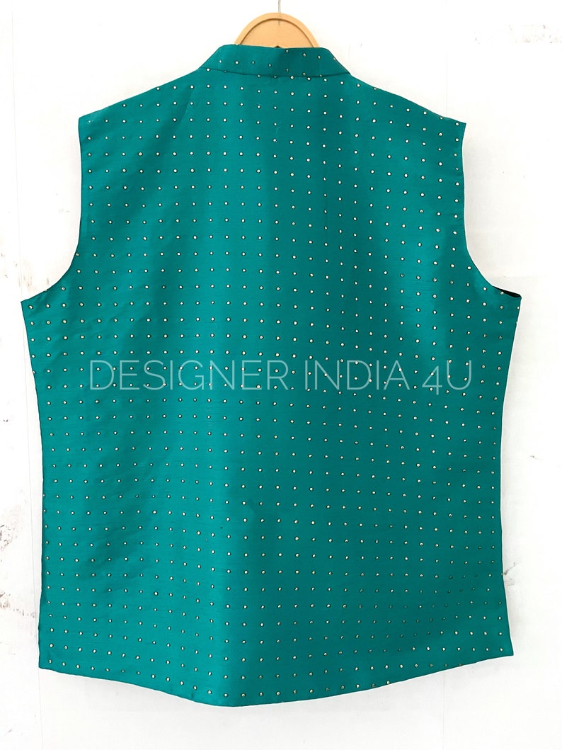 May include: A teal sleeveless vest with a small, white dot pattern. The vest has a mandarin collar and a button closure. The text "DESIGNER INDIA 4U" is printed on the back of the vest.