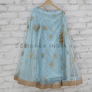 May include: A light blue skirt with gold embroidery and a gold tassel. The skirt is made of a sheer fabric and has a flowing silhouette.