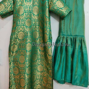 May include: A two-piece green and gold brocade outfit. The top is a tunic with short sleeves and a round neckline. The matching pants have a flared hem. The fabric has a floral pattern.