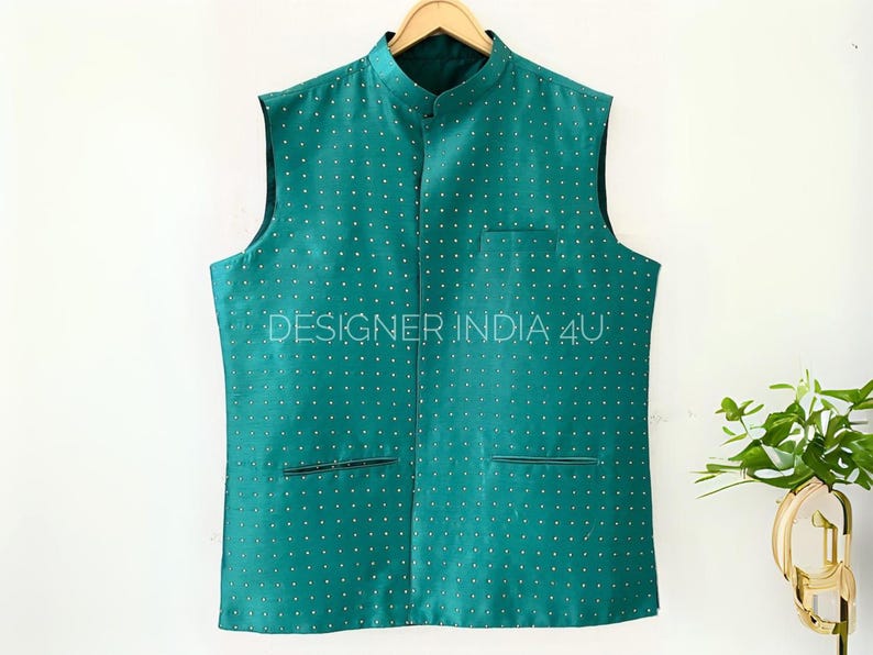 May include: A teal blue sleeveless vest with a mandarin collar and a white polka dot pattern. The vest has two pockets and the text "DESIGNER INDIA 4U" is printed on the front.